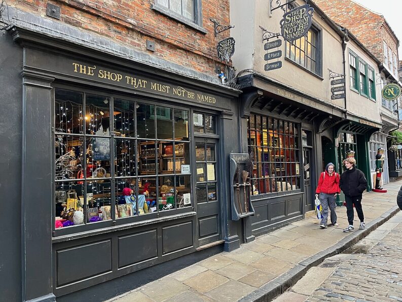 The Shambles in York, a cobbled medieval street with timber-fronted shops including 'The Shop That Must Not Be Named'
